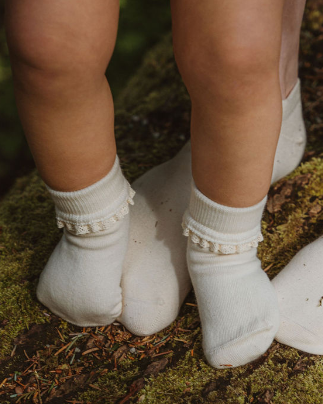 Kids and toddler white organic cotton ankle socks with lace trim standing on moss | Q for Quinn