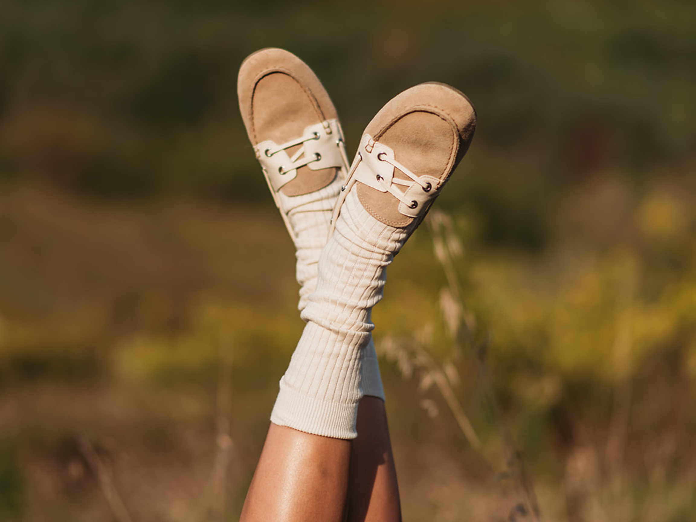 Feet wearing brown sandals and white socks with a blurred natural background
