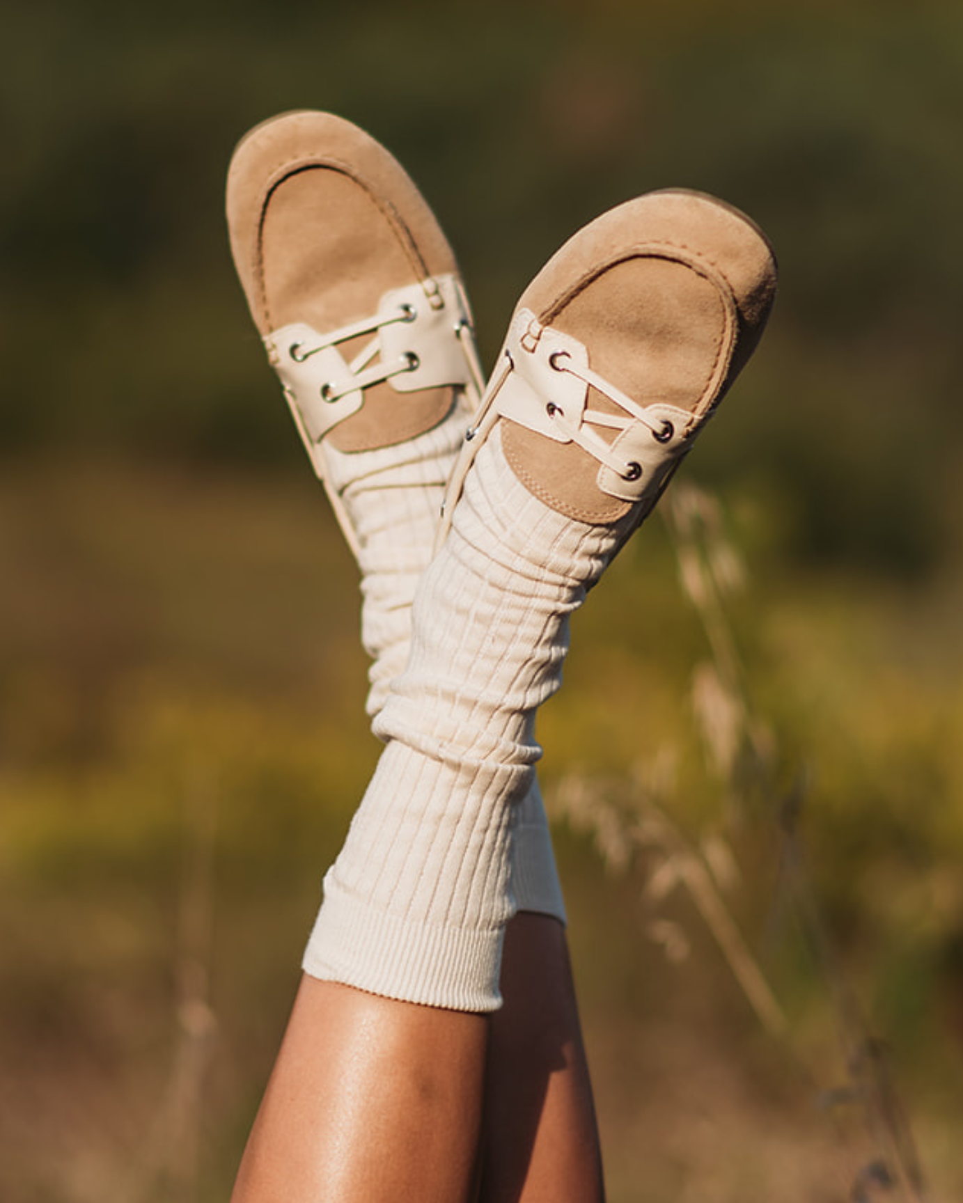 Feet wearing brown sandals and white socks with a blurred natural background