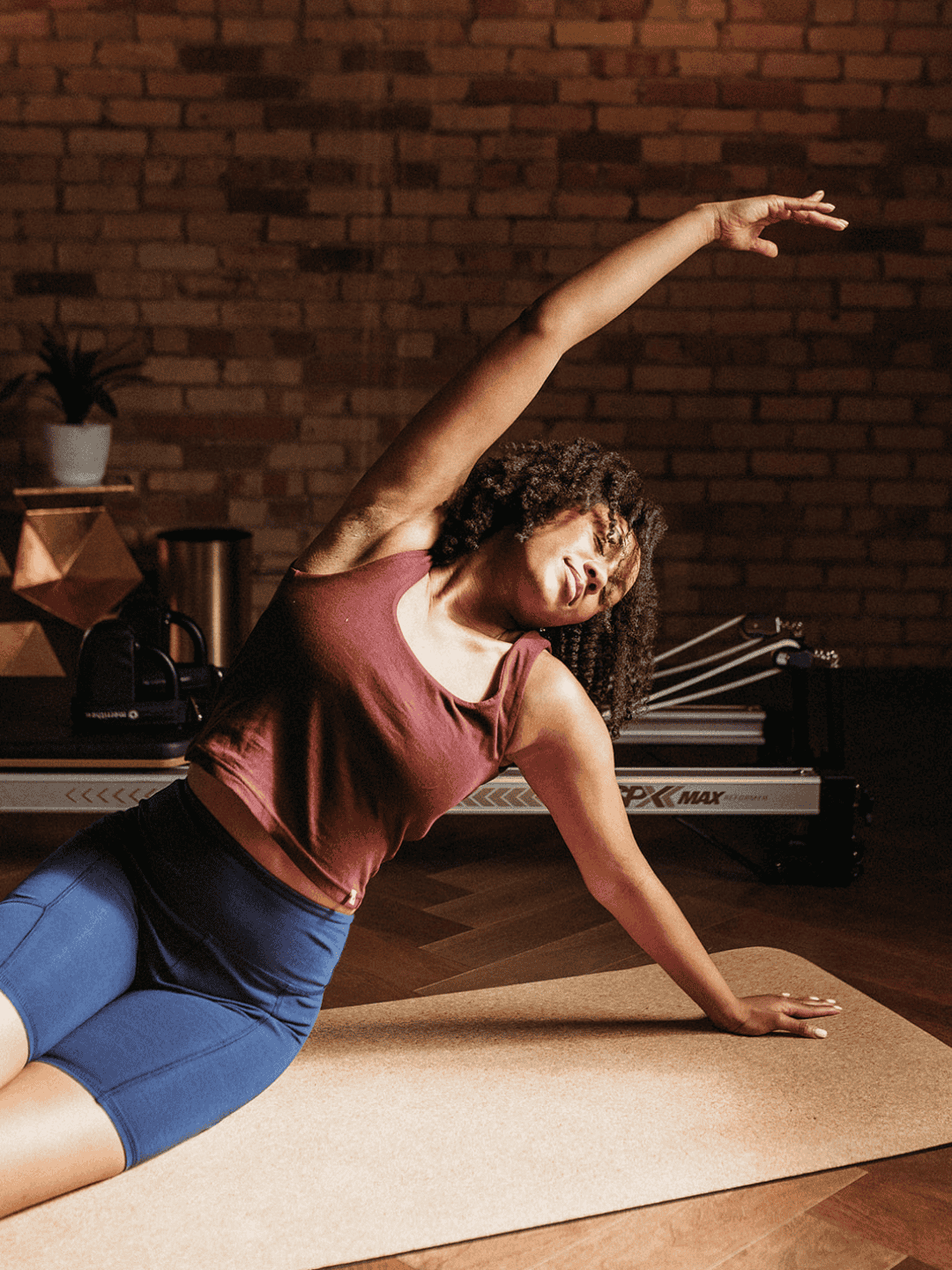 Woman practicing yoga in a home setting with a brick wall background