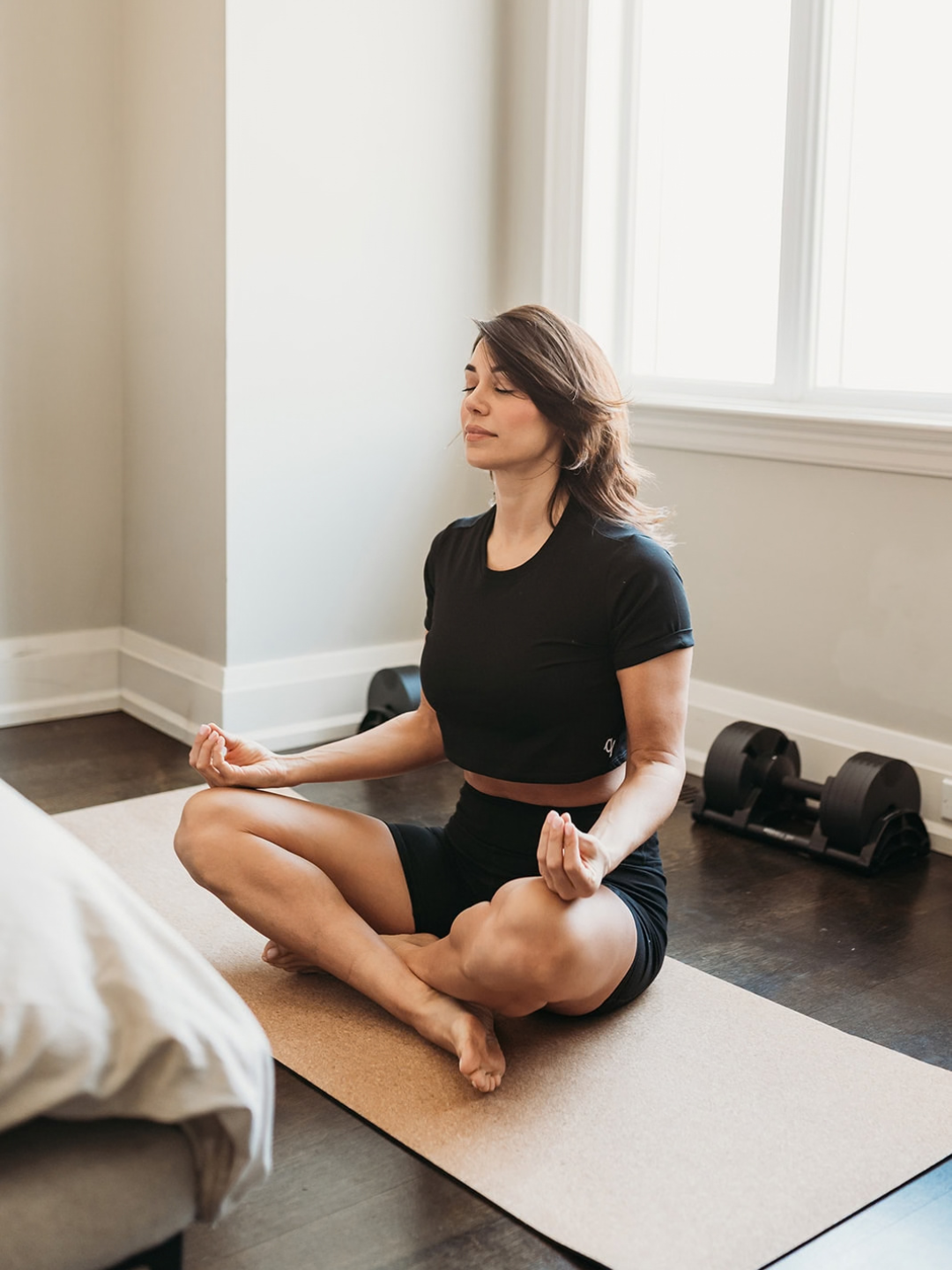 Woman practicing yoga in a home setting with a window in the background