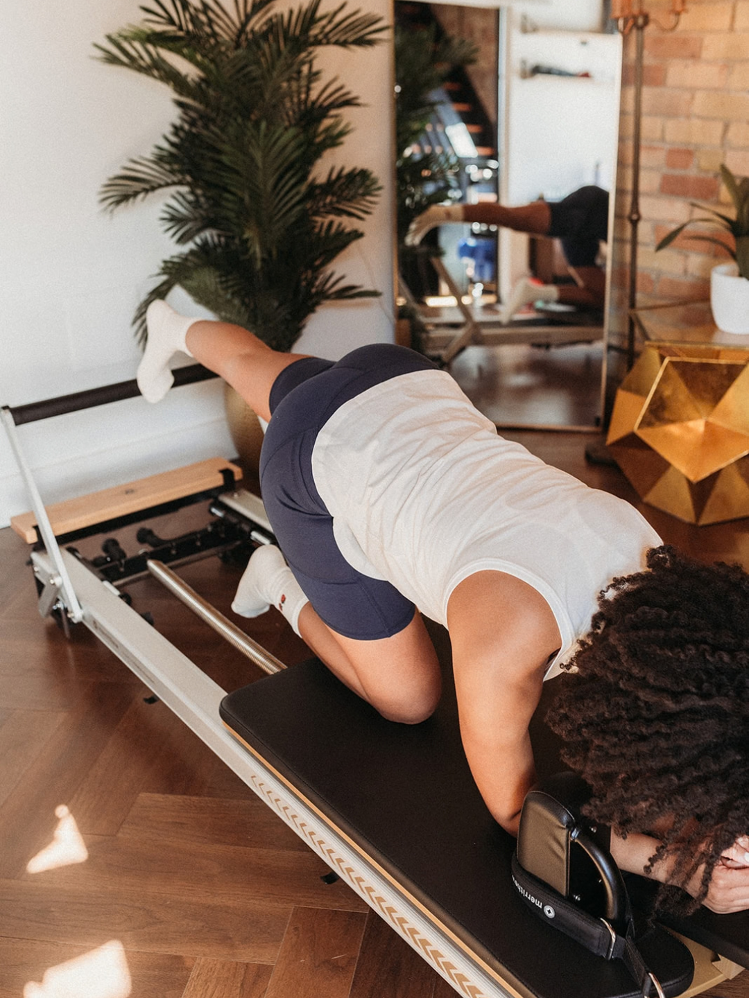 Person doing Pilates on reformer wearing white organic cotton socks and navy biker shorts | Q for Quinn