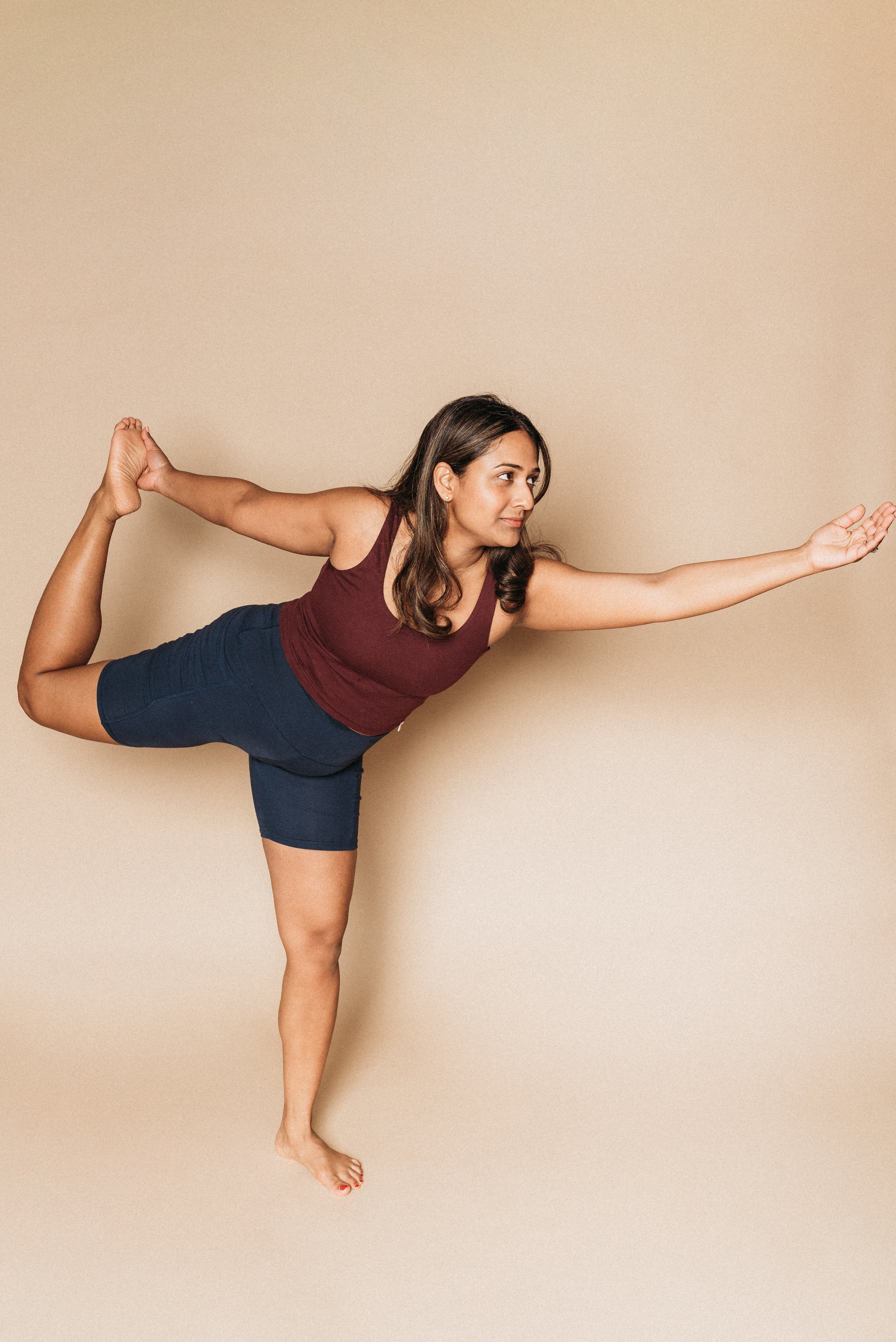 Woman wearing Shelf Tank and Biker Shorts, doing dancer's pose.
