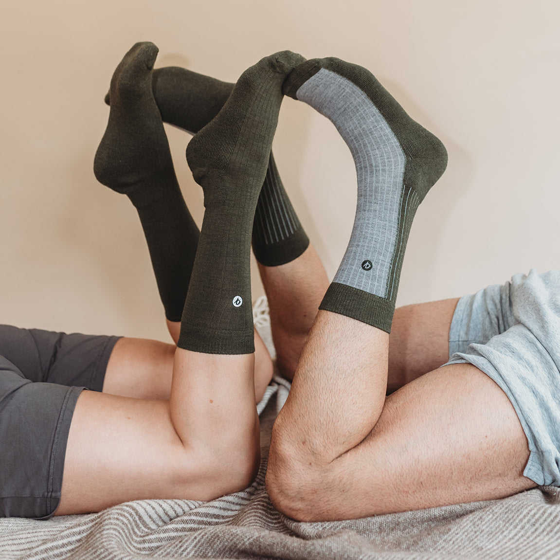 Two pairs of feet wearing green socks on a beige background