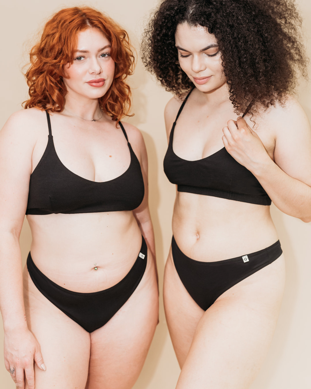 Two models wearing Women's Stretch Thong in Black with matching organic cotton bralettes | Q for Quinn