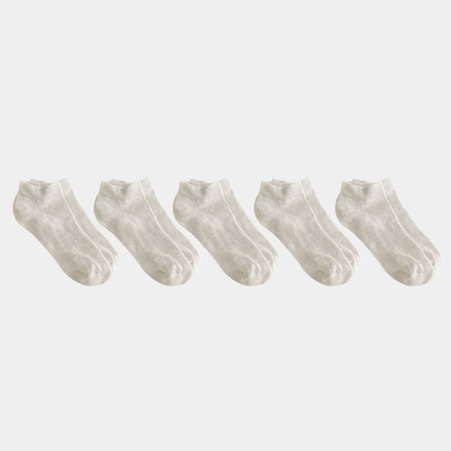 Set of five white ankle socks on a light gray background