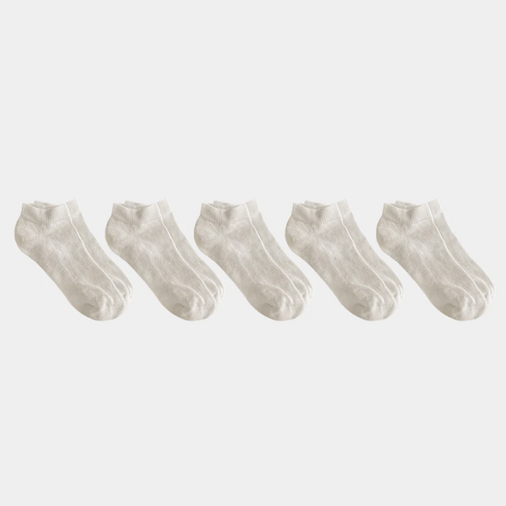 Set of five white ankle socks on a light gray background