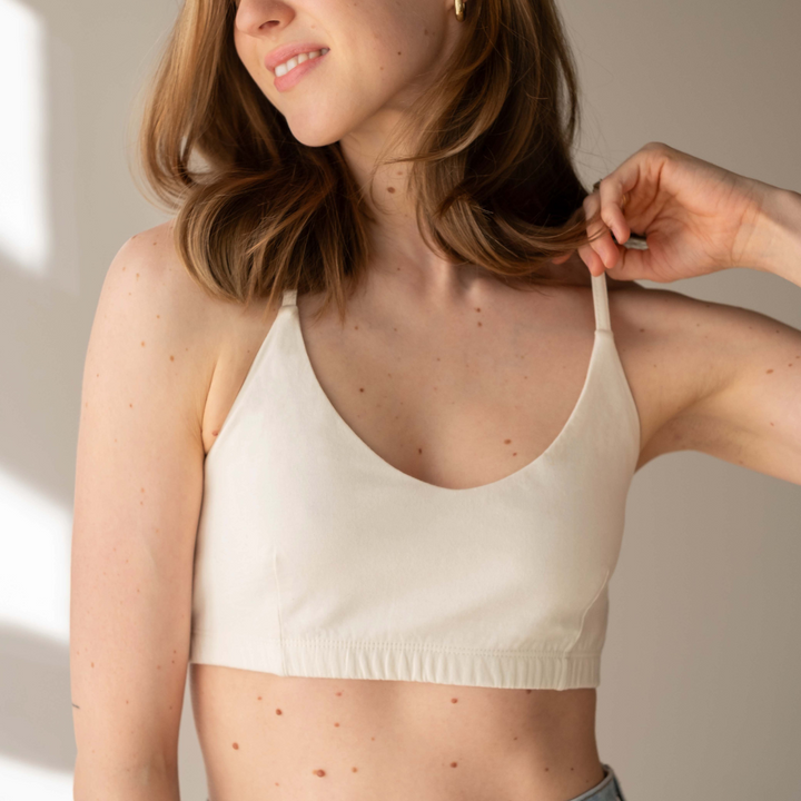 Woman wearing a beige bralette against a neutral background