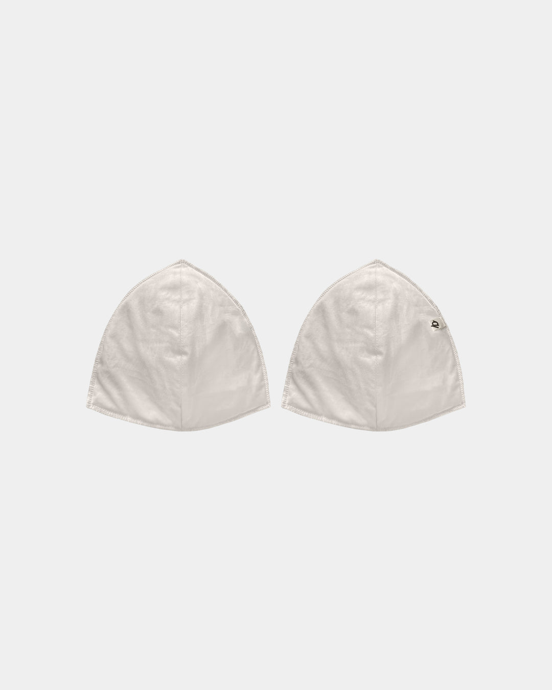Two off-white cotton capes with a small black embroidered logo on the right cape, displayed side-by-side on a light gray background.