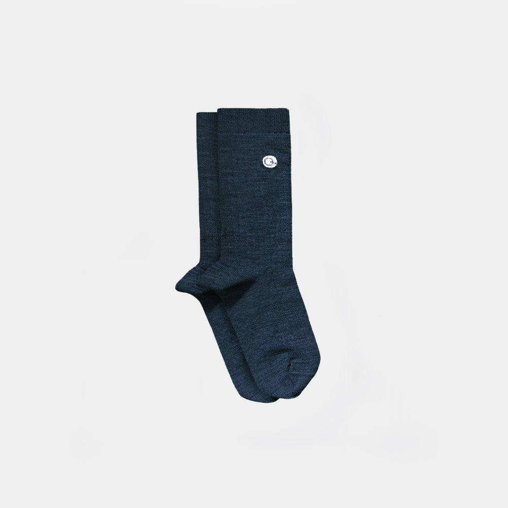 A pair of dark green heathered crew socks with a small white circular logo on the upper cuff, displayed against a solid light gray background.