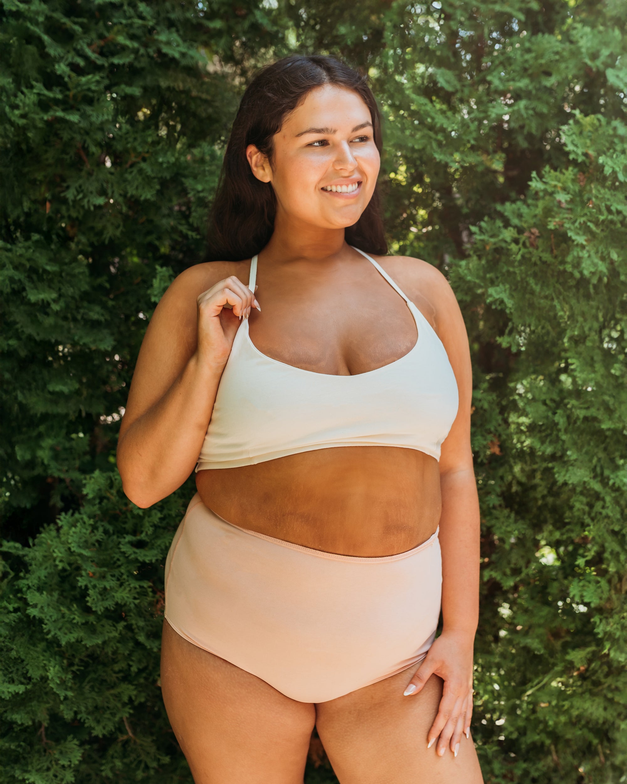 Model outdoors in Women's High Waist Brief in Dark Nude, green trees in background | Q for Quinn