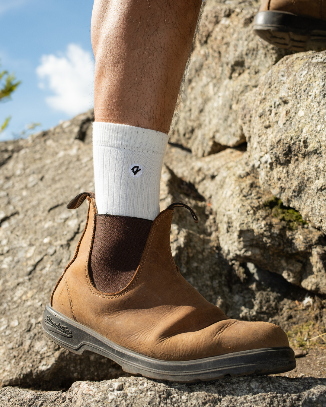 White ribbed crew sock worn with tan Chelsea boot on rocky outdoor terrain | Q for Quinn