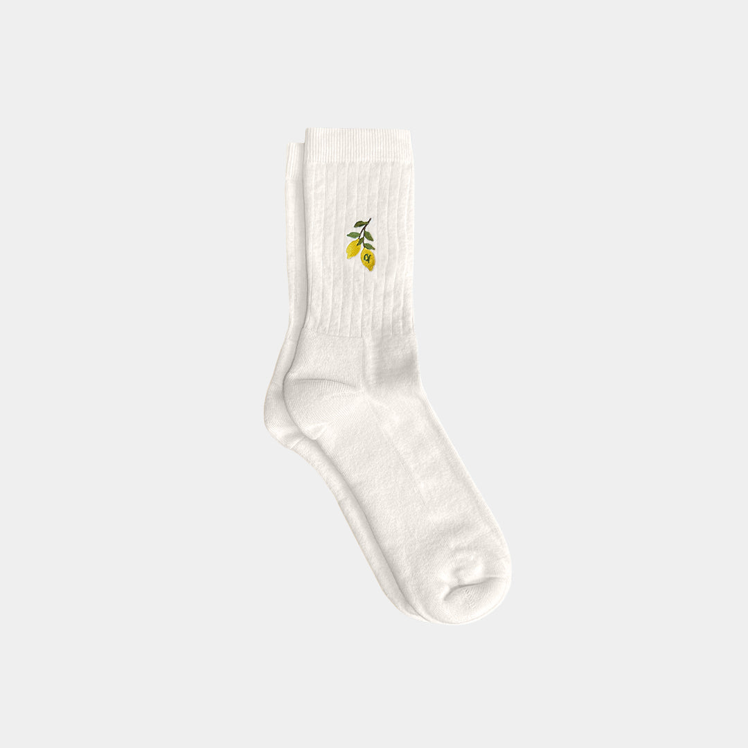 White sock with a small green and yellow design on a light gray background