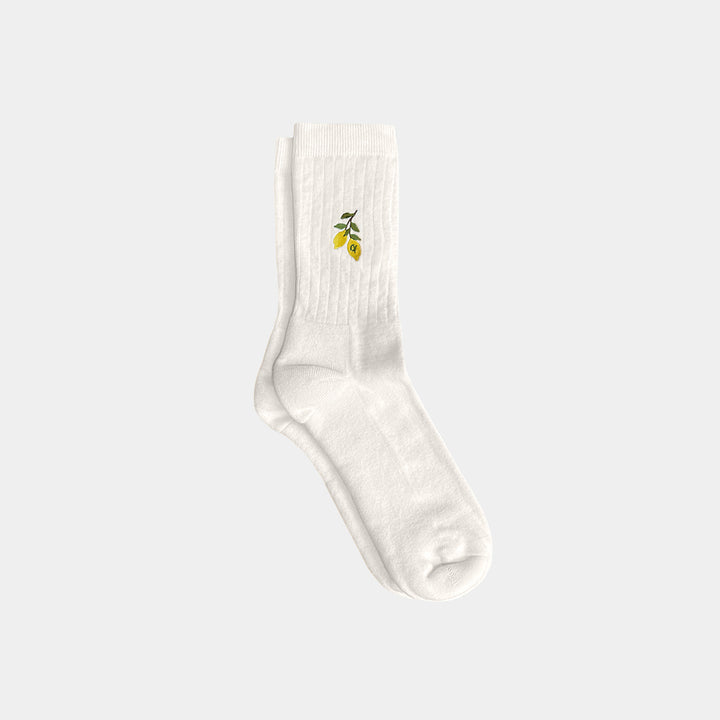White sock with a small green and yellow design on a light gray background