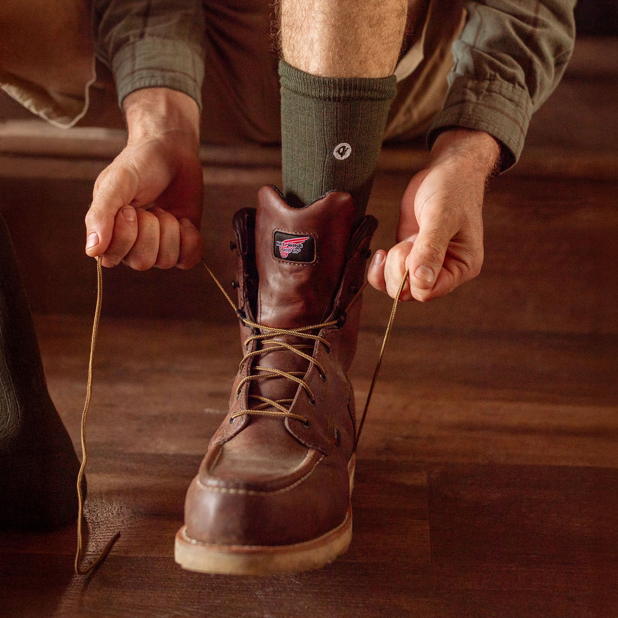Person lacing up leather work boots wearing Merino Wool Cotton Midweight Adult Socks Multipack in Moss | Q for Quinn