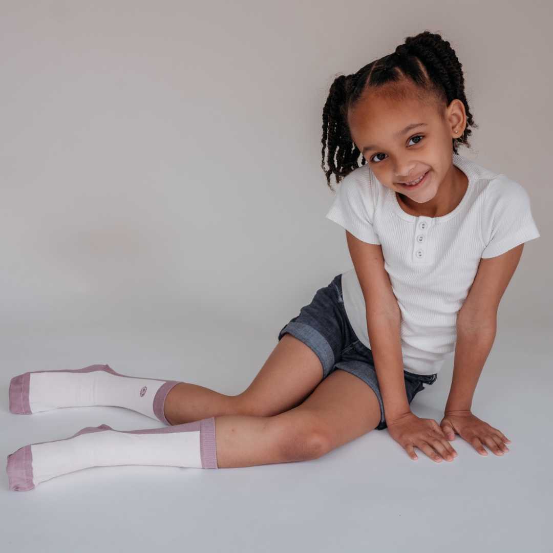 A little girl smiling wears organic cotton socks