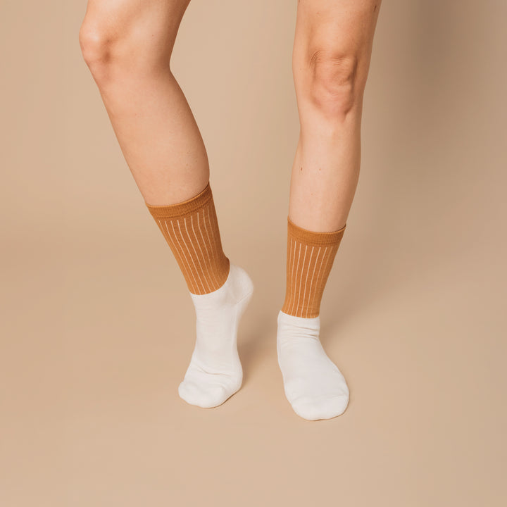 Person wearing brown knee-high socks and white socks on a beige background
