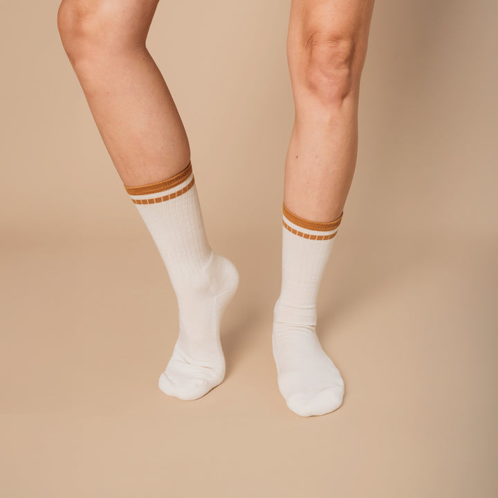 White socks with brown stripes worn by a person on a beige background