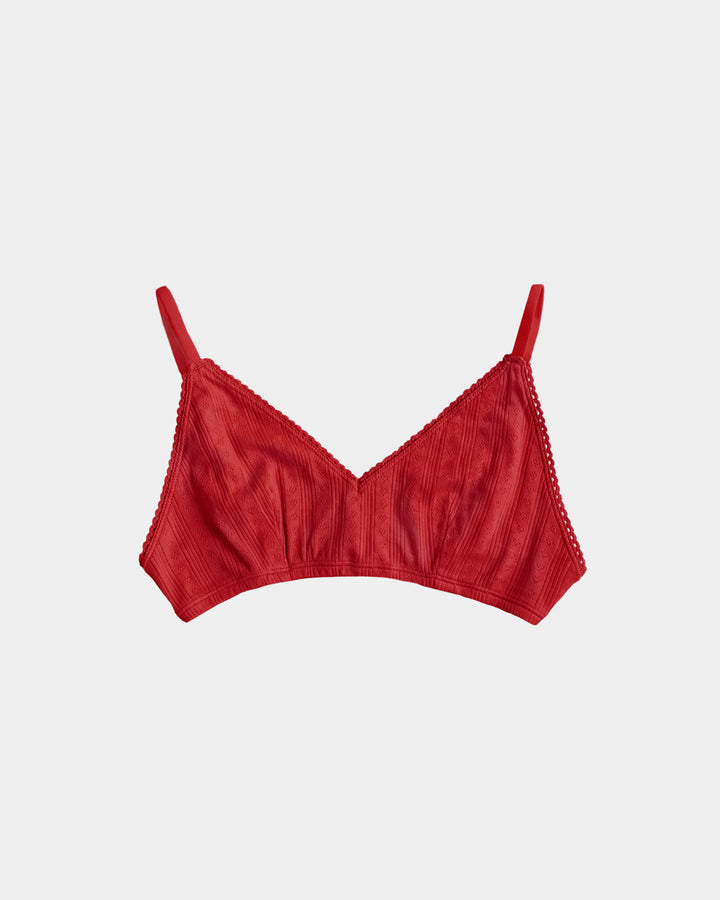 A red ribbed triangle bralette with thin shoulder straps and delicate lace trim along the edges, shown flat against a light gray background.