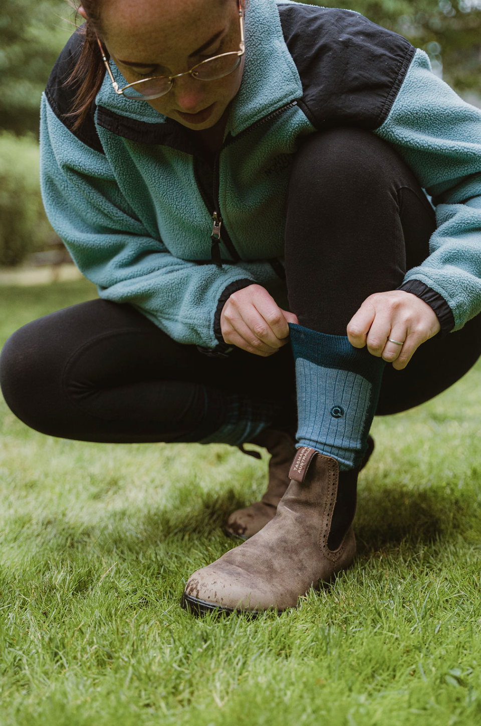 Person adjusting a boot on grass