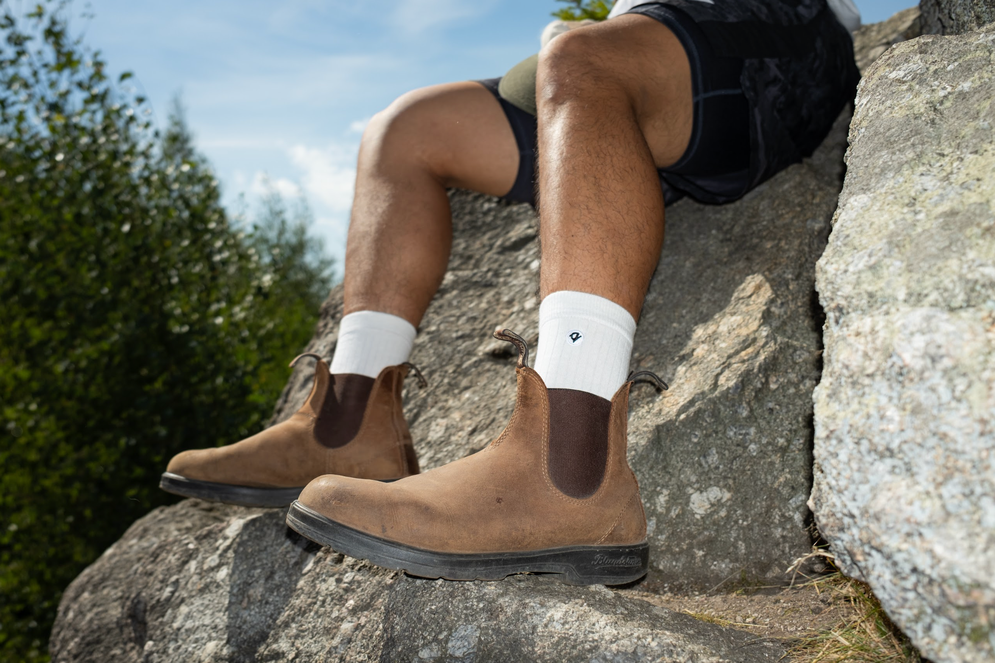 Person wearing Q for Quinn white socks and boots on a cliff
