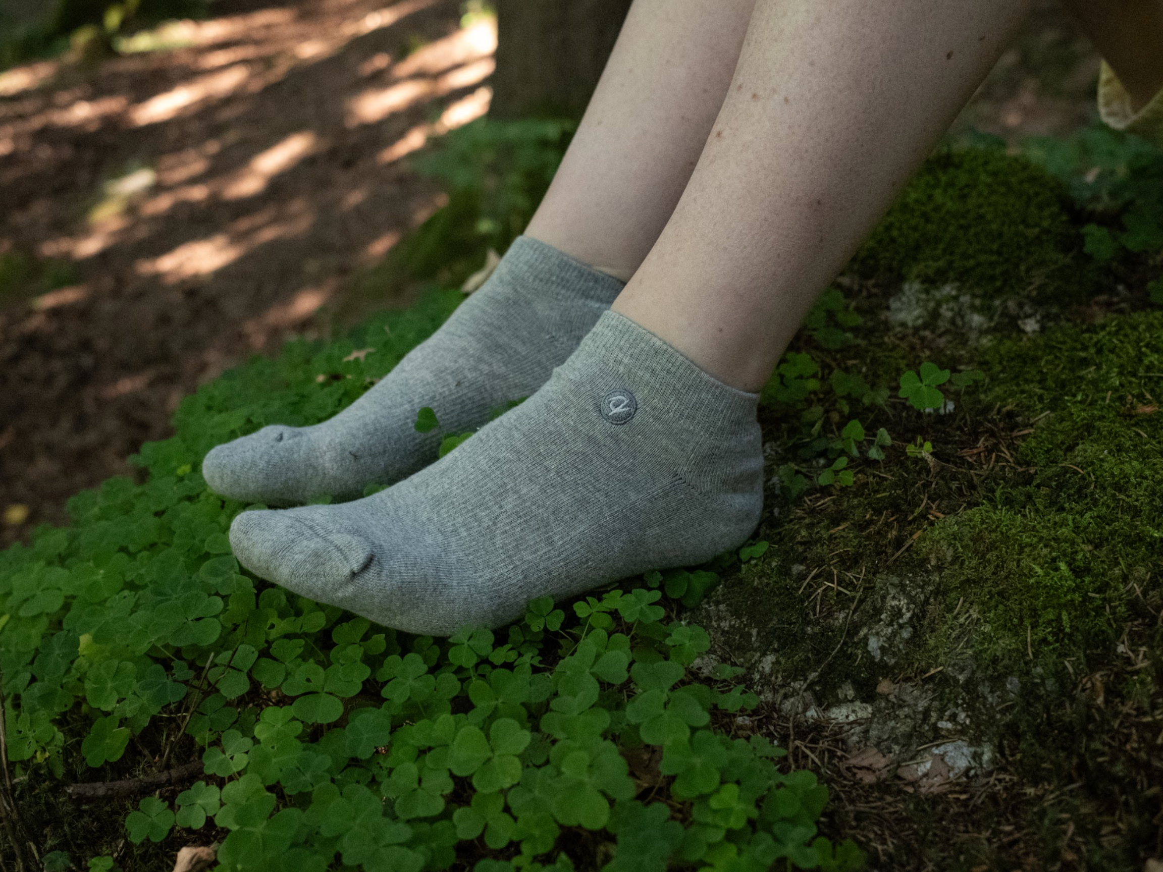Gray socks worn on feet standing on a mossy surface