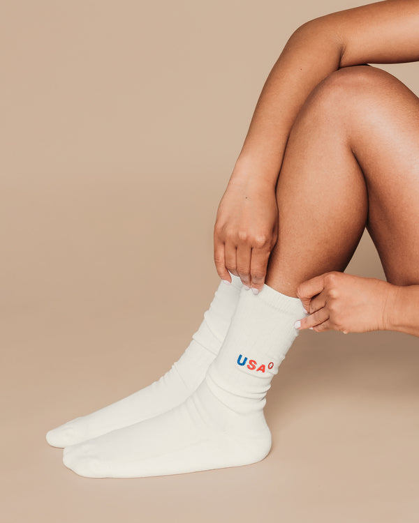 Person wearing white socks with 'USA' text on a beige background