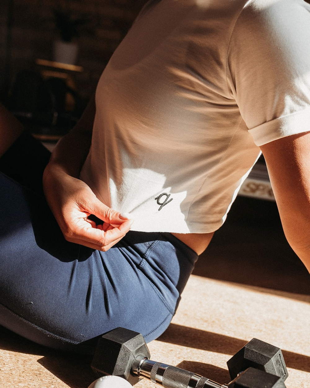 Woman stretching crop tee to show 'Q' logo