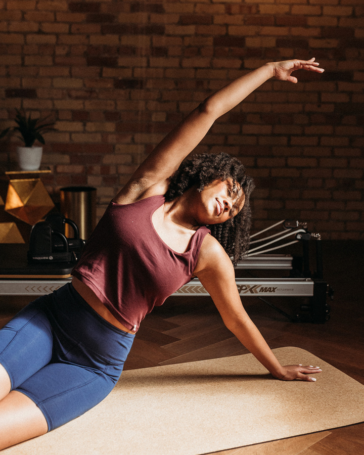 Woman practicing yoga in a home setting with a brick wall background