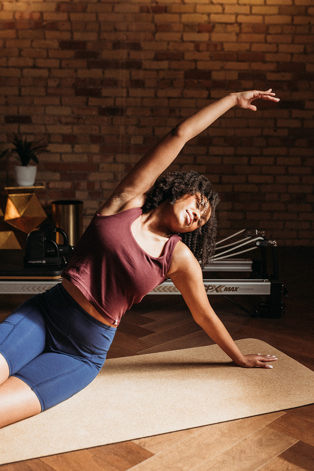 Woman stretching on a yoga mat in a home setting with a brick wall background