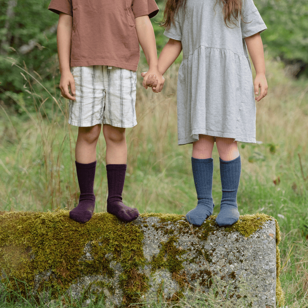 two children holding hands, wearing merino wool socks