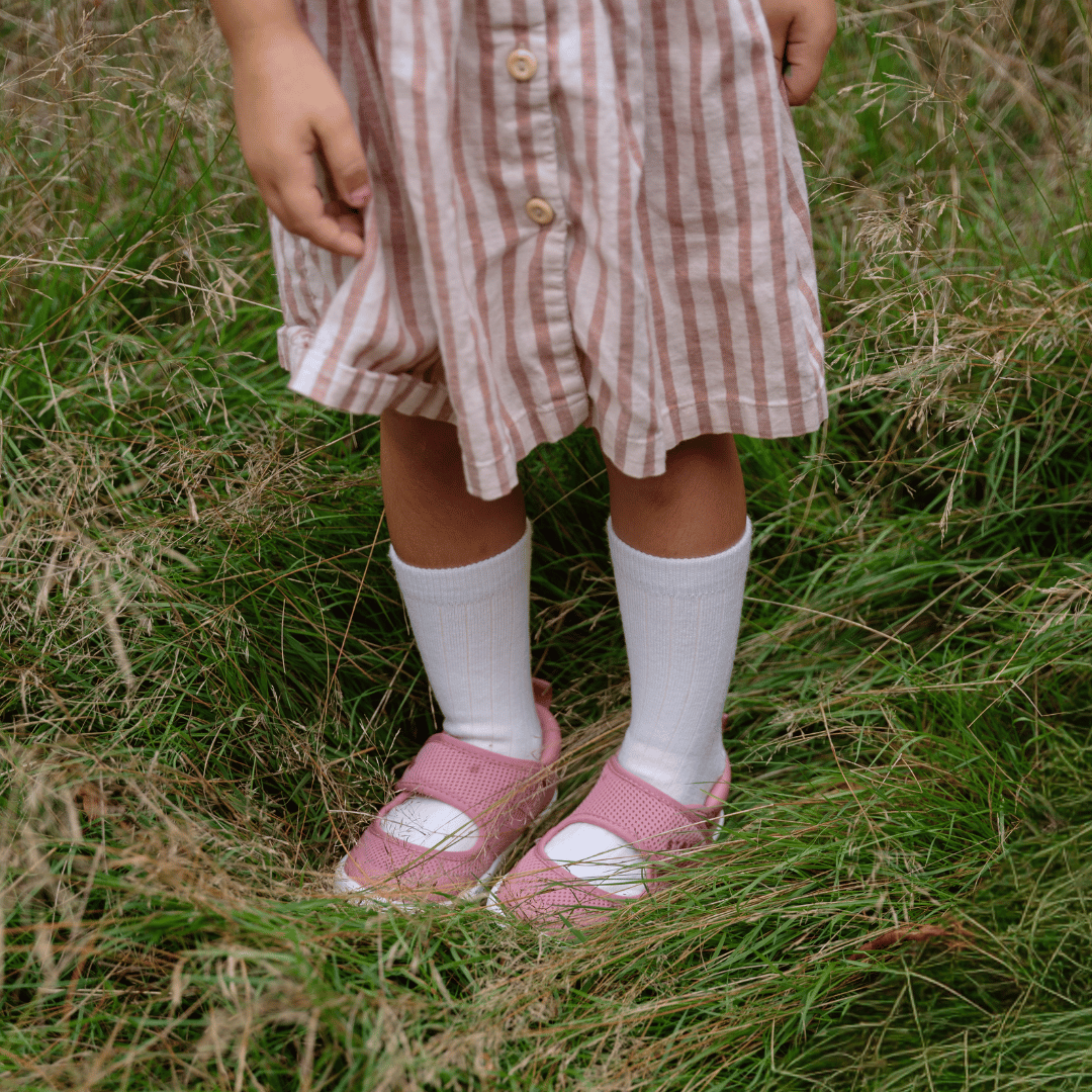 Child wearing white merino wool socks in grass