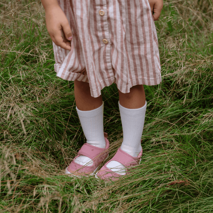 Child wearing white merino wool socks in grass