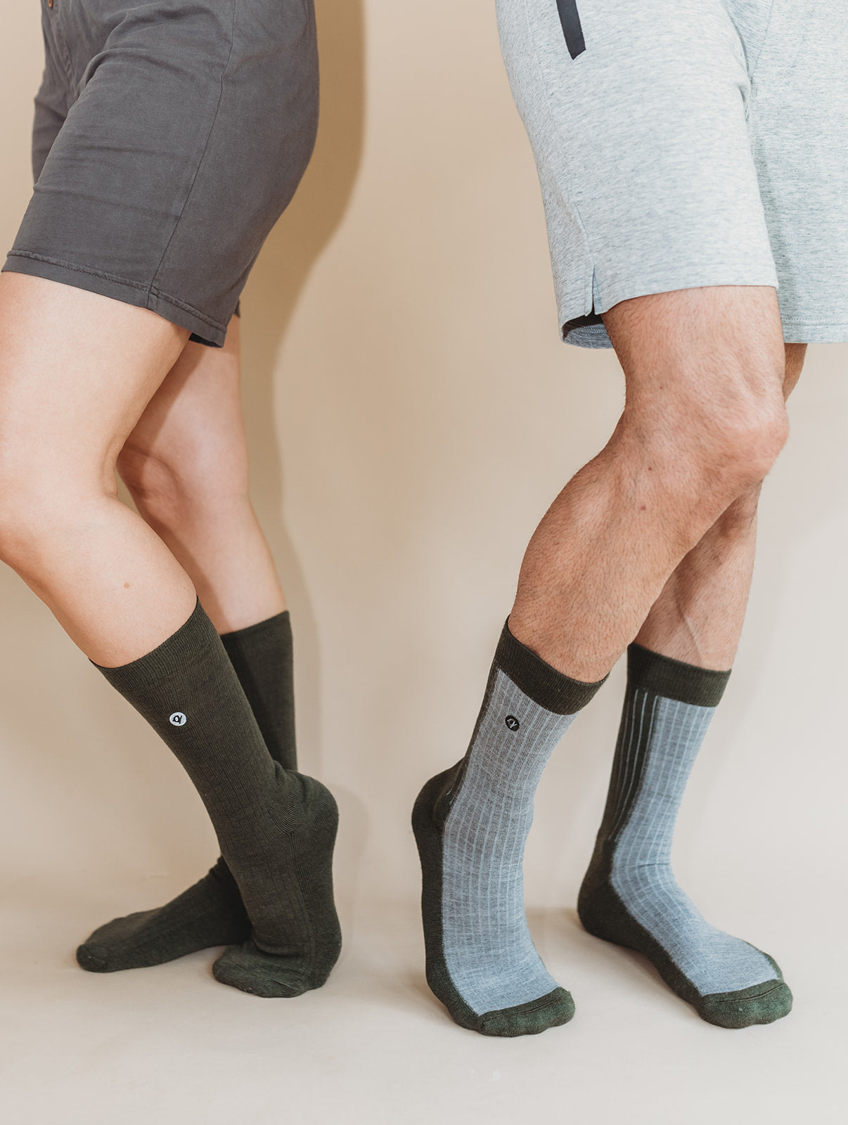 Two pairs of legs wearing socks on a plain background