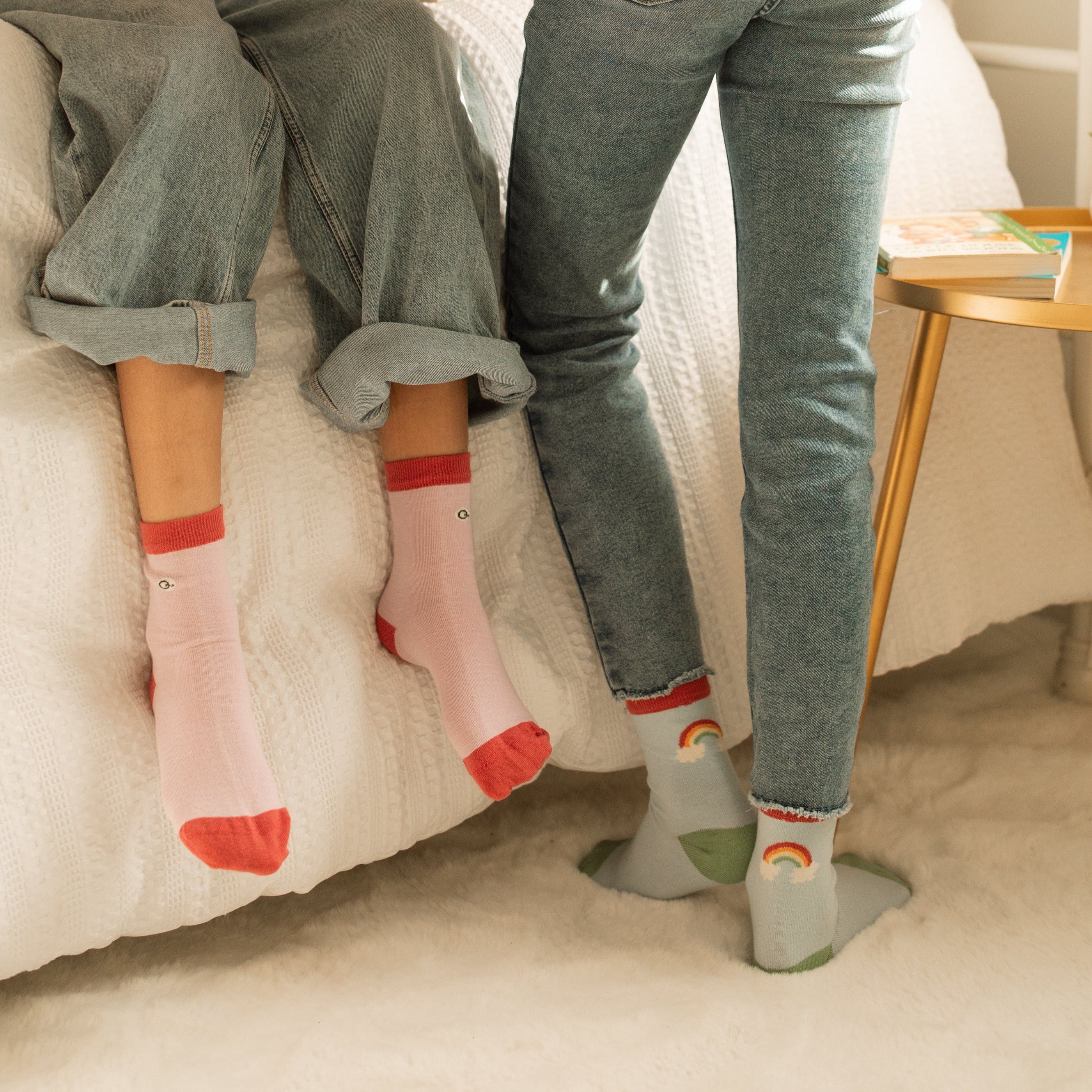 Two children sitting on a bed wearing Mixed Patterns Kids Organic Cotton Socks in pink and grey rainbow patt | Q for Quinn