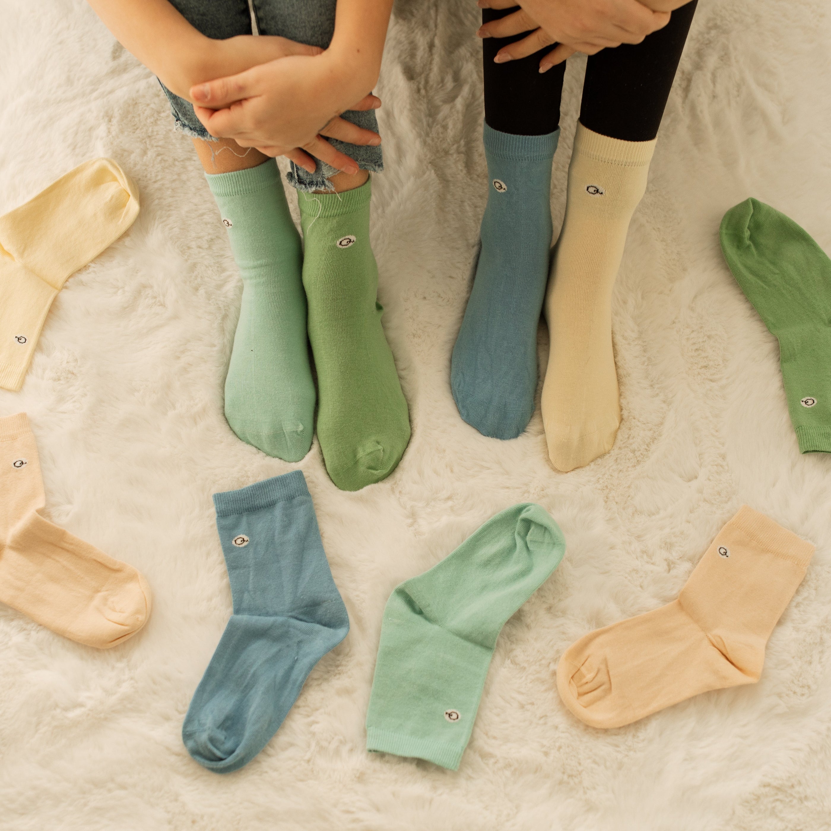 Organic Pastels Kids Organic Cotton Socks in green, blue, cream, and peach displayed on children's feet on f | Q for Quinn