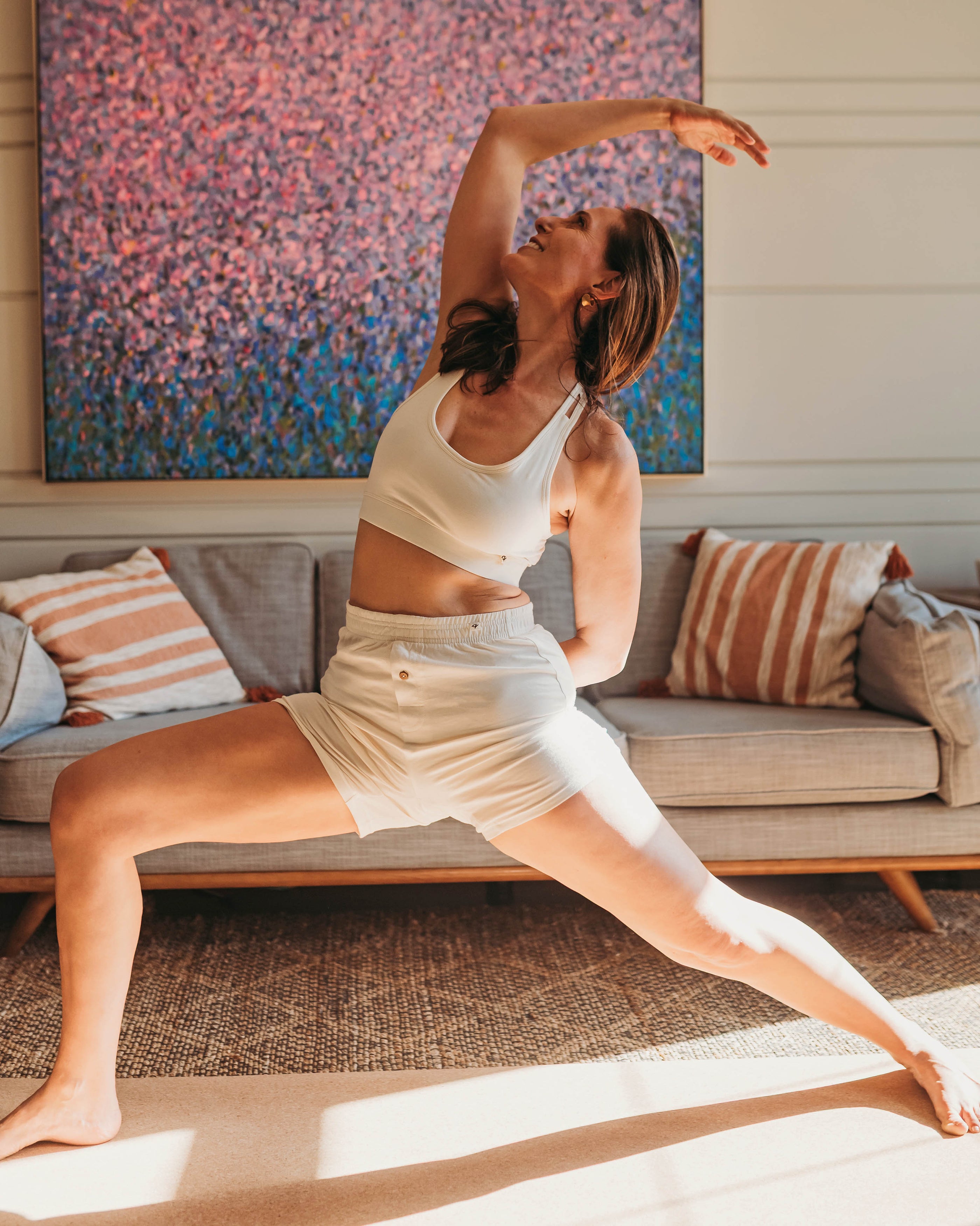 Woman doing a yoga lunge indoors wearing Organic Racerback Sports Organic Cotton Bra in Natural with matchin | Q for Quinn