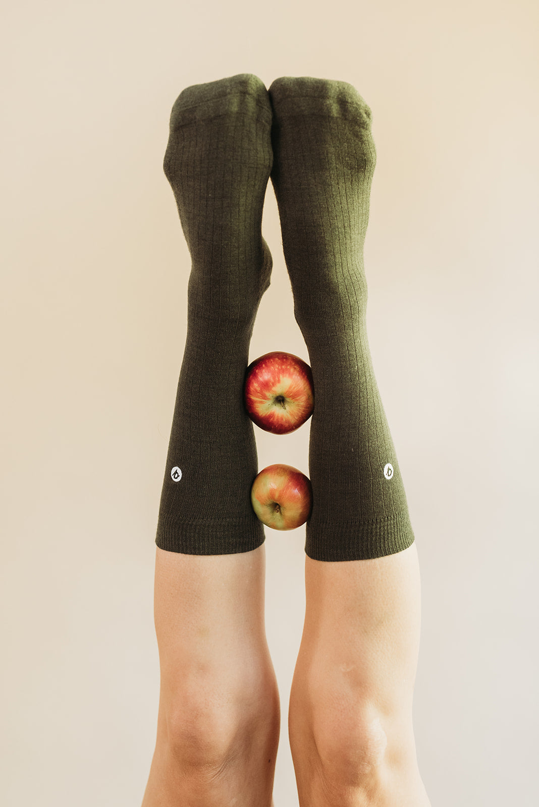 Green knee-high socks with apple design on a beige background