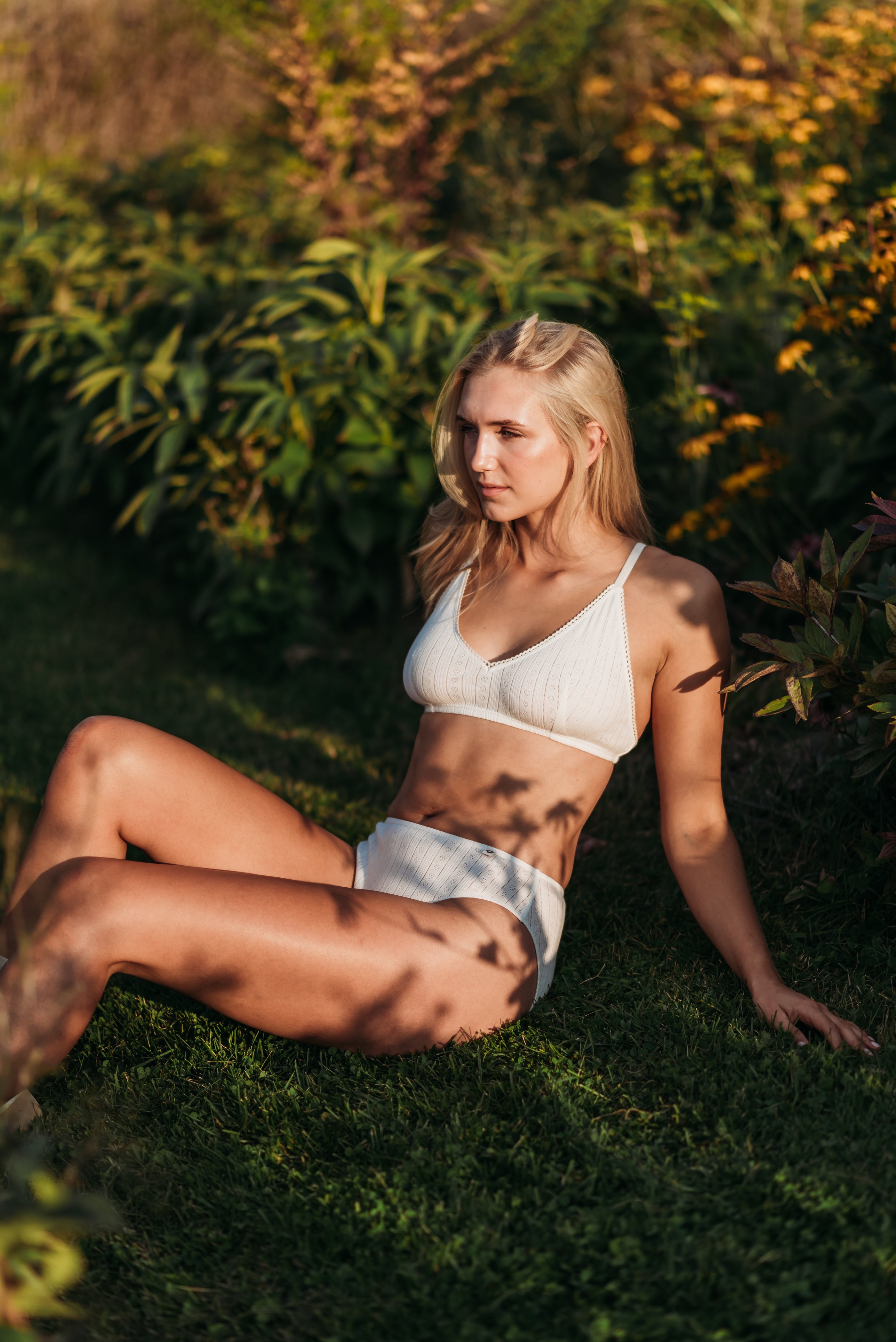 Woman wearing natural (no dye) Pointelle Bra and French Cut Bikini Set, lying in a field of grass.